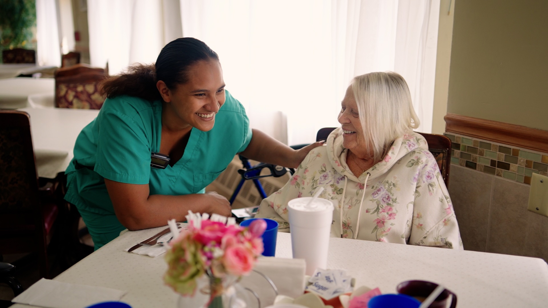 caregiver-smiling-with-resident-dining-room-cedar-woods-assisted-living