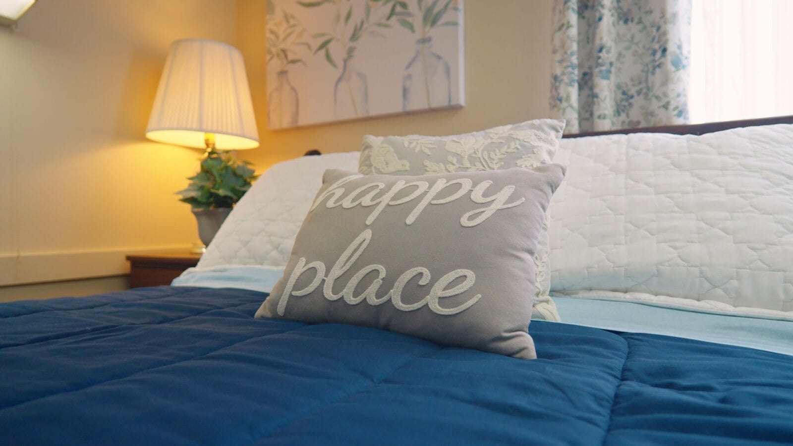 Decorative ‘happy place’ pillow on a neatly made bed inside a resident room at Cedar Woods Assisted Living in Belleville, Michigan.
